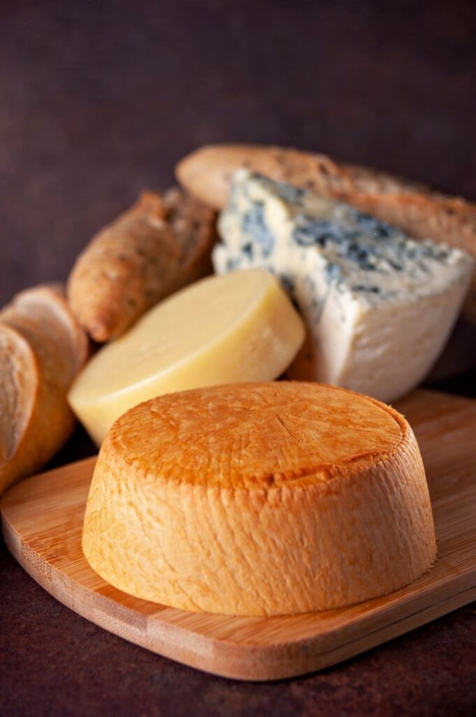 A variety of artisanal cheeses and bread displayed on a wooden board, ideal for gourmet presentations.