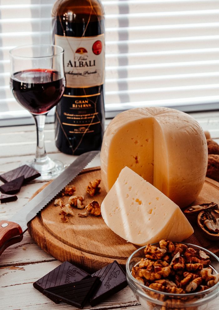 A sophisticated setup of wine, cheese, nuts, and chocolate on a wooden board, perfect for a romantic dinner.