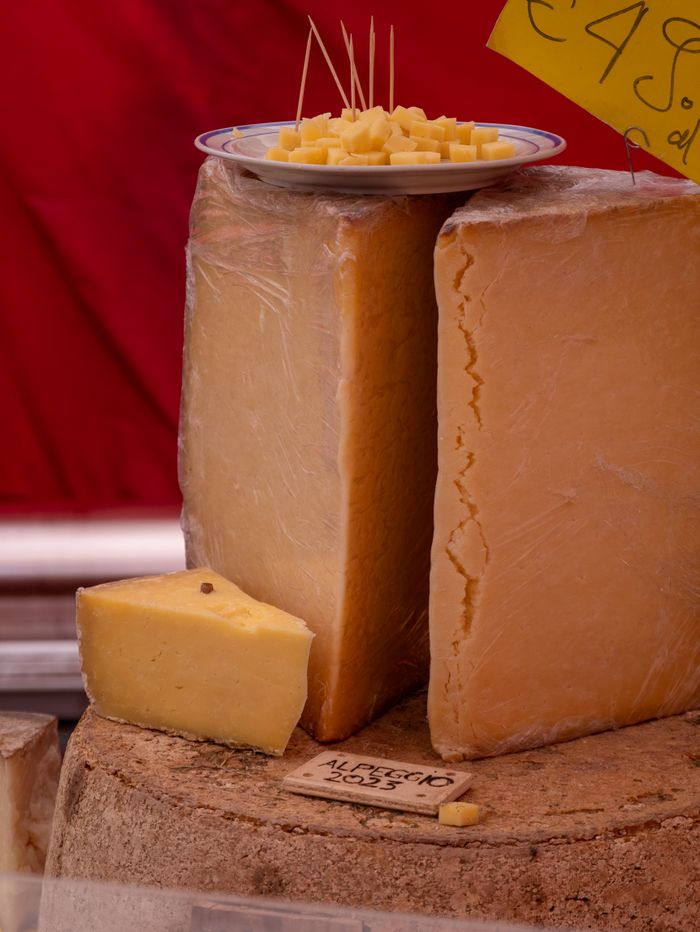 Tantalizing cheese wedges on display with sampling plate at a market stall.