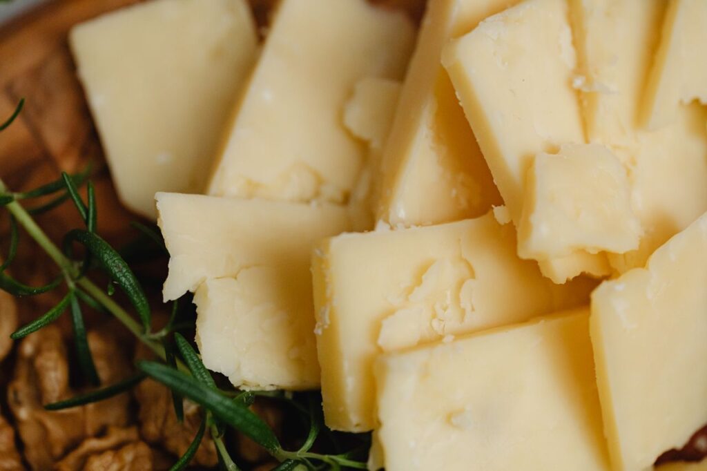 Pile of sliced cheese with rosemary and walnuts, perfect for food photography.